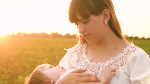 Junge Mutter wiegt ihr Baby bei Sonnenuntergang in Zeitlupe — Stockvideo