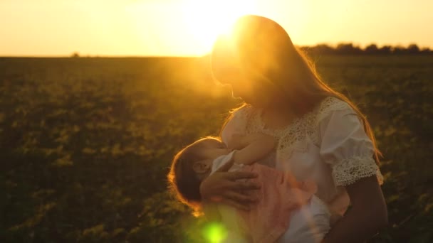 Madre camina con un niño pequeño en el parque de verano al atardecer, el niño se duerme en las manos de las madres, disparos en cámara lenta — Vídeos de Stock