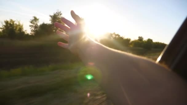 Girl waves her hand from the car window and catches beautiful glare of the sun. Slow motion. — Stock Video