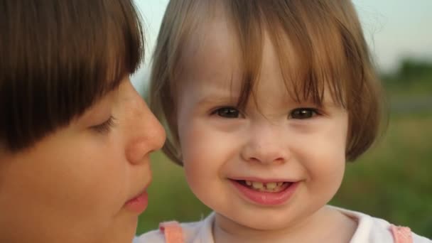 Bambino piccolo tra le braccia della sorella sorride e mostra il dito nella macchina fotografica, passeggiata in famiglia nel parco in estate, rallentatore — Video Stock