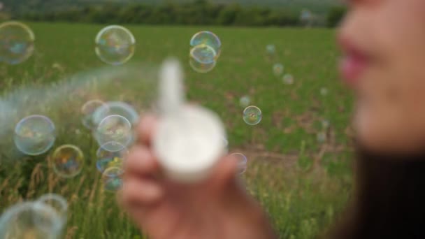 Frau pustet transparente Seifenblasen gegeneinander und lächelt. Zeitlupe — Stockvideo