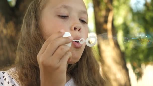 Tienermeisje verhuurt zeepbellen en glimlacht in een zomer-park. — Stockvideo