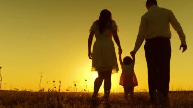 Baba ve anne küçük bebek onun elele günbatımı altın güneş ışınları ile oynarken.