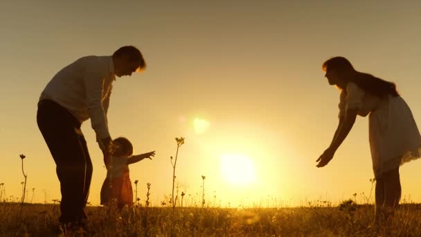 Um bebé pequeno com a família aprende a andar ao pôr-do-sol. Movimento lento . — Vídeo de Stock