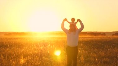 Mutlu baba ayı Bebek onun omuzlarında, kahkaha ve altın güneş batımında oturma. Ağır çekim.