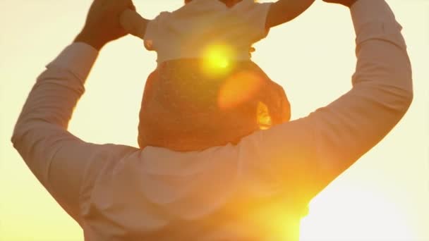 Dad carries his beloved child on his shoulders at sunset. Slow motion. — Stock Video
