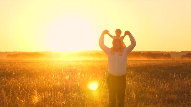 Glücklicher Papa trägt Baby auf seinen Schultern, bei Sonnenuntergang der goldenen Sonne und lacht. Zeitlupe. — Stockvideo