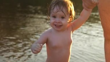 Bir şekilde gülerek el ve plaj boyunca yürüyüş babası tutan gülümseyerek mutlu bir çocuk. Yakın çekim