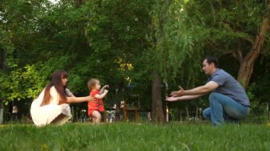 Bebek çim çimen üzerinde anne ve baba ile ilk adımlar alır.