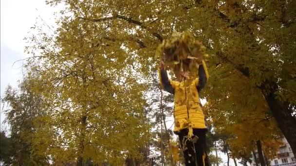 Meisje gooit herfst geel laat omhoog en het lijkt erop dat ze vallen. Slow motion — Stockvideo