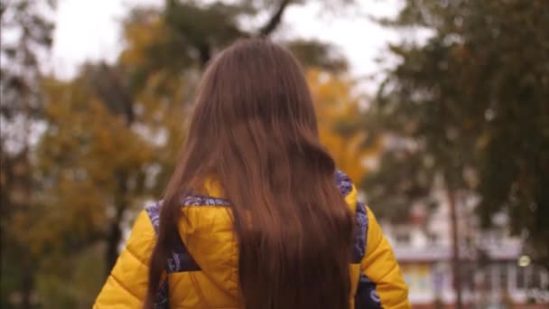 Girl with long hair goes along road ahead. Slow motion. — Stock Video