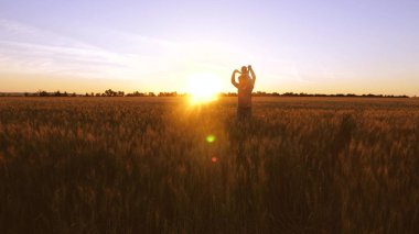 Babamla dans gülen ve buğday alanında altın günbatımı planda küçük bebek.