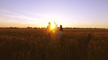 Çocuk ailesi ile alan golden sunset ışınlarının buğday ile yürür. Bebek anne ve baba oynamak ve buğday alanıyla gülmek.