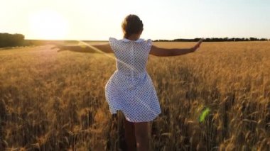 mutlu küçük kız ağır çekim alanındaki günbatımı arka planda, olgun buğday, uçuyor