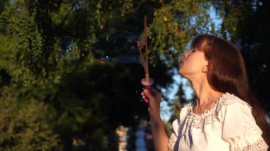 Güzel kız güzel, büyük sabun köpüğü ve gülümsüyor sağlar. Ağır çekim.