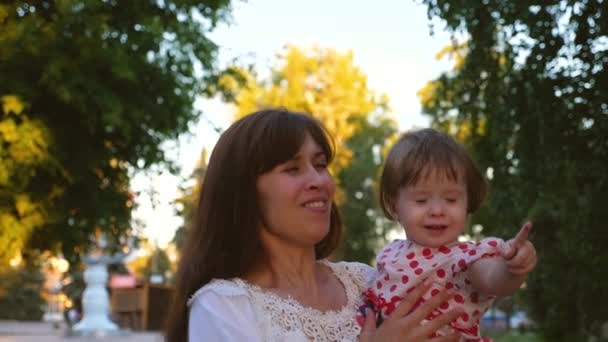 Gelukkig moeder met kleine baby barst haar handen met grote transparante zeepbellen, lacht en glimlacht. Slow motion — Stockvideo