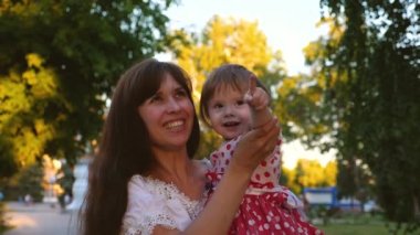 Mutlu bebek anne hugs ve büyük şeffaf sabun köpüğü, gülüyor ve gülümsüyor patlamaları. Ağır çekim