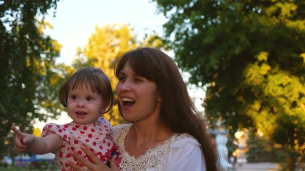 Щаслива мама з маленькою дитиною розриває руки великими прозорими мильними бульбашками, сміється і посміхається. Повільний рух — стокове відео