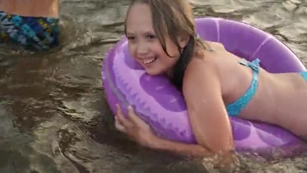 Дівчина в купальнику плаває вниз по річці у воді на рятувальному житті і сміється. Пляжний сезон — стокове відео