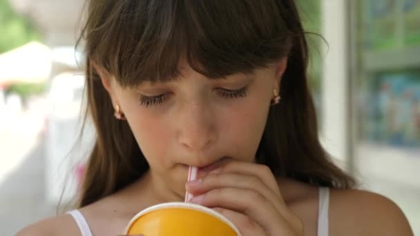 Meisje drinkt SAP uit buis in stad etalage in de middag en glimlacht. Close-up — Stockvideo