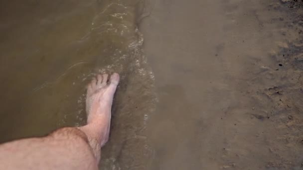 Man loopt langs kust spatten druppels in verschillende richtingen. Beach seizoen. Slow-motion. Close-up — Stockvideo