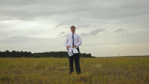 Geschäftsmann in weißem Hemd und Krawatte spielt mit fliegendem Flugzeug aus Papier und lächelt vor dem Hintergrund dunkler Wolken — Stockvideo