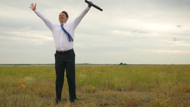 Empresario en camisa blanca y corbata con maletín en mano bailando torbellino en vuelo sobre fondo de nubes oscuras y sonriente — Vídeos de Stock