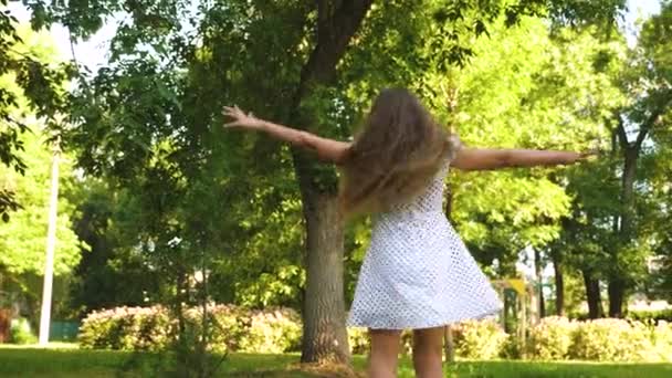Dança menina feliz e redemoinhos em vestido branco em um parque de verão . — Vídeo de Stock