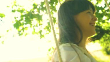 Parlak altın günbatımı hızıyla üzerinde sallanan ve gülümseyen uzun saçlı güzel kız. Ağır çekim