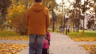 Baba onun önüne bir sonbahar parkında küçük bebek arabası alır. Ağır çekim