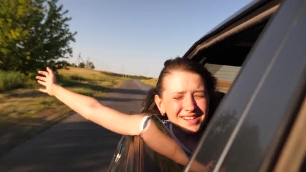 Muchacha joven agitando su mano desde la ventana del coche en la luz del sol brillante, cámara lenta — Vídeo de stock