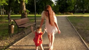 Çocuk yaz aylarında yol park boyunca yürümeyi öğrenir, Anne ile bebek yürüyor