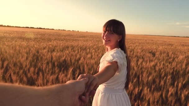 Smějící se dívka běží přes pole pšenice upínání mans ruku v záři zlaté slunce. Zpomalený pohyb. — Stock video