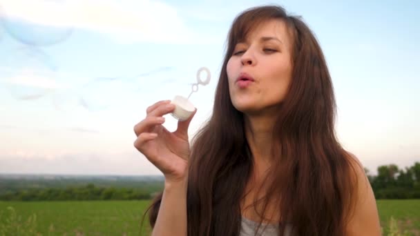 Kobieta dmuchanie bańki mydlane przezroczyste przeciw błękitne niebo i smill. Zwolnionym tempie. — Wideo stockowe