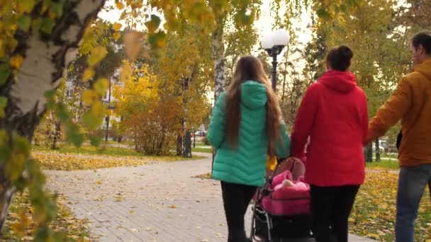 Niño pequeño con sus padres camina en el parque caliente en otoño por la tarde — Vídeos de Stock