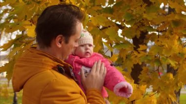 Bebek ve baba dokunmatik altın, sonbahar yaprakları ve gülümseme.