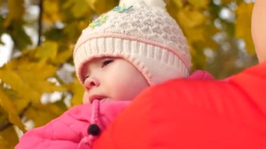 Küçük bebek annesinin kollarında sonbaharın altın yaprağı sonbahar Park'ta size yürür