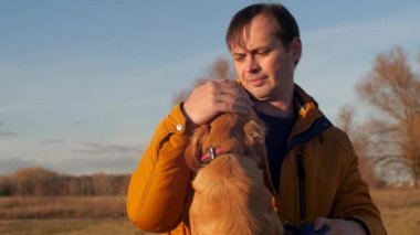 sahibi ile bir köpek parkta sonbaharda yürür. Adam köpek okşayarak. portre