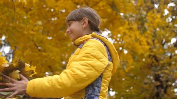 Mädchen wirft Herbstblätter nach oben und lächelt. Zeitlupe. — Stockvideo