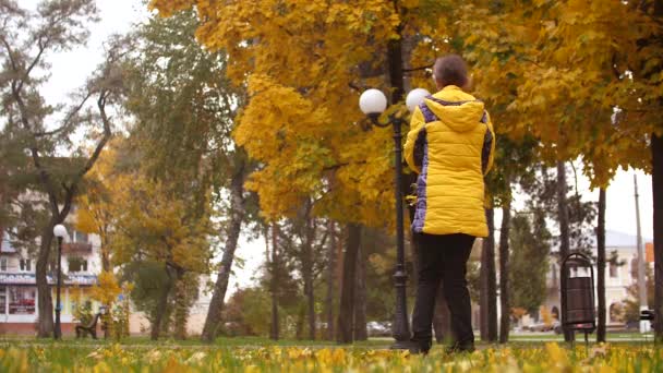 Девушка бросает осенние листья вверх и улыбается. Медленное движение . — стоковое видео