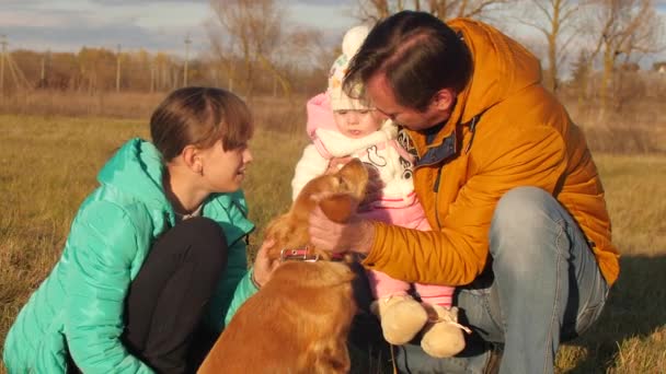 Dog licks proprietors nose, who walks with his children. — Stock Video