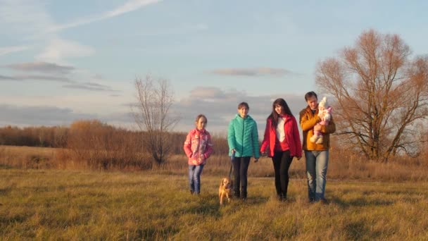 Las niñas con los padres caminan en el parque junto con el perro con correa y hablar, sonreír . — Vídeo de stock