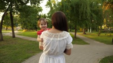 Mutlu bebek anne kollarında oturan ve parmak yaz parkta gösteren gülümseyen. Ağır çekim