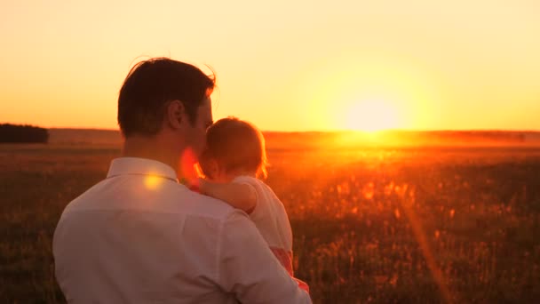 Papá camina con un niño pequeño en sus brazos en el parque nocturno en otoño al atardecer. Papá e hija pasan un día libre juntos. . — Vídeos de Stock