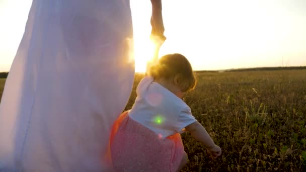 Niña va adelante sosteniendo su mano madre en la puesta del sol brillante — Vídeos de Stock