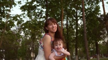 Anne Çocuk eğlencesine sokakta hava atar. Bebek sevgi dolu anne boyuyla güler. Bebek ve anne gülmek, birlikte parkta yürüyüş için oynama.