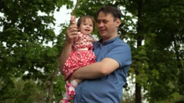 Anne-baba ile çocuk elini sallayarak ve yeşil park gülümseyen