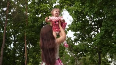 Bebek annesi havada uçan ile gülüyor. Çocuk oyun ve ailesi Park ile yürüme gülümseyen. Ağır çekim.