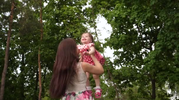 Mamá lanza al bebé alto en el aire, riendo y jugando con ella en el parque . — Vídeo de stock