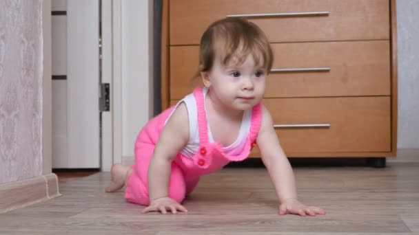 Маленький ребенок ползает по полу в детской комнате — стоковое видео